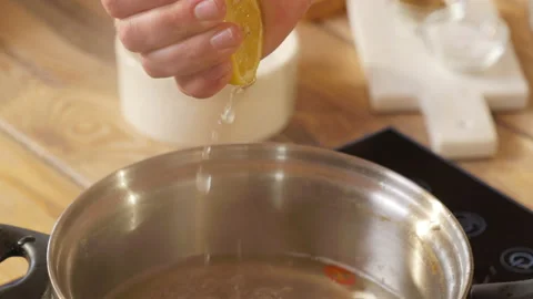 The hand squeezes out a lemon. Lemon juice. Soup. Sauce with a lemon Stock Footage 162620805