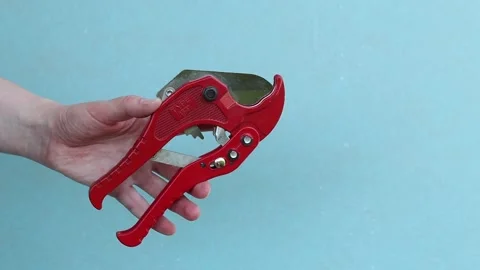 Hand squeezes red scissors for cutting PVC and polypropylene pipes Stock Footage 338003428