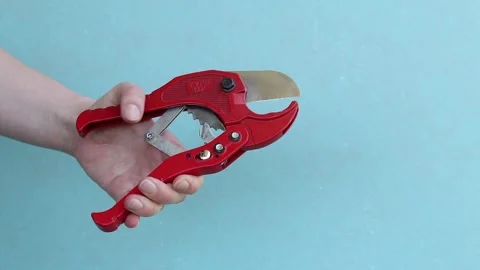 Hand squeezes red scissors for cutting PVC and polypropylene pipes Stock-Footage 338003440