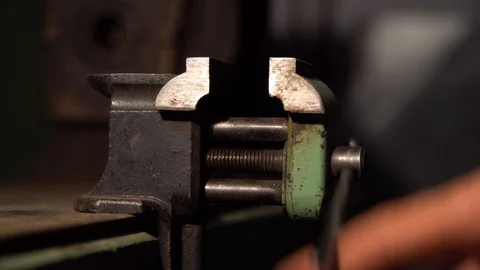 The hand squeezes small engineering vice.That is fixed on the table Stock Footage 126749325