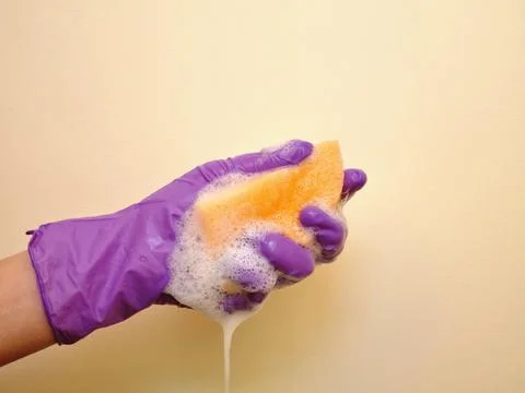 A hand squeezes a sponge with foam Stock Photos