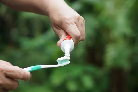 Hand squeezes toothpaste on toothbrush. Stock Photos