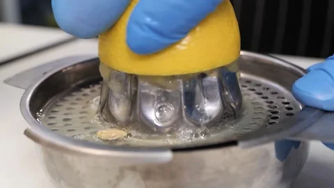 Hand Squeezing Fresh Lemon Juice with a Manual Stainless Steel Juicer Stock Footage 331956688