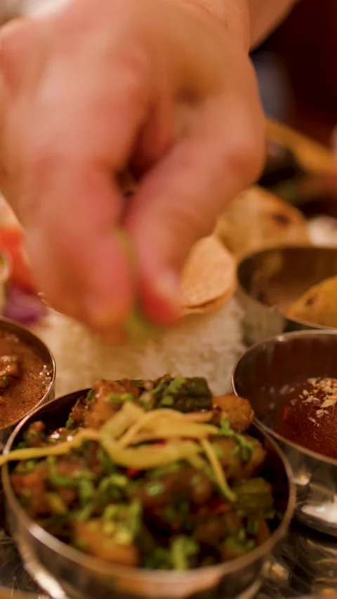 Hand Squeezing Fresh Lime Over Traditional Indian Thali Platter Stockbeeldmateriaal 337535519