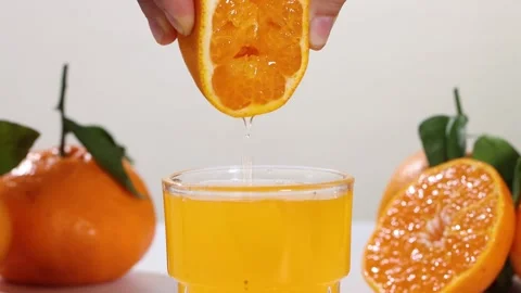 Hand Squeezing Fresh Orange Juice into Glass Close Up Stock Footage 340451966