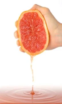Hand squeezing a grapefruit to a large amount of juice Stock Photos