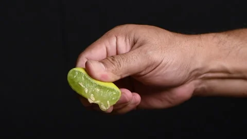 Hand squeezing half of lemon on black background. Stock Footage 207466136
