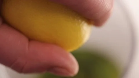 Hand squeezing half of lemon in a bowl on white background Stock Footage 122095735