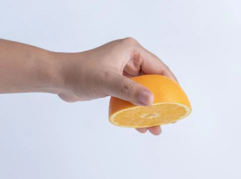 Hand squeezing a half orange fruit Stock Photos