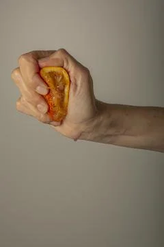 Hand squeezing half a red orange to make juice Stock Photos