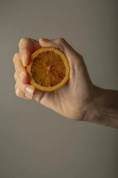 Hand squeezing half a red orange to make juice Stock Photos