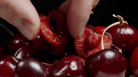 Hand Squeezing Juice from Cherry Half, Berries on Black Background, Macro. Slow Stock Footage 278320049
