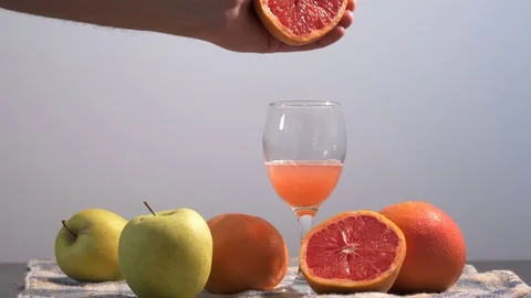 Hand squeezing juice of grapefruit or orange into glass in slow motion Stock Footage 83856222