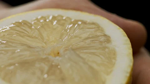 A hand squeezing the juice from a lemon half Stock Footage 128721491