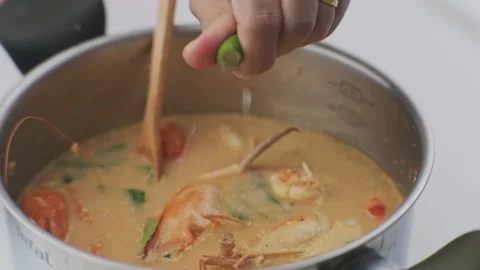 Hand squeezing lemon close up. Spicy prawn soup. Stock Footage 242965125