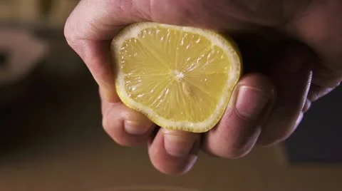 Hand squeezing lemon on dark background Stock Footage 21653516