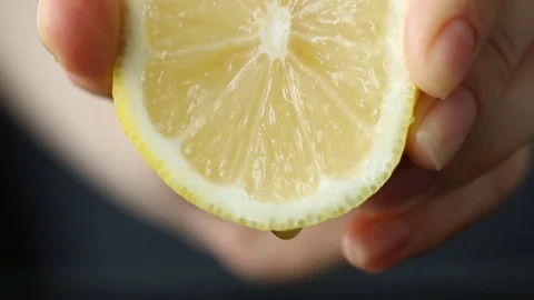 Hand squeezing lemon on dark background Stock Footage 77722518