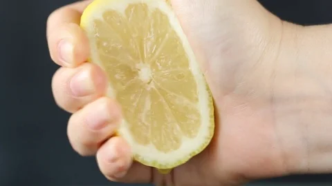 Hand squeezing lemon on dark background Stock Footage 77722552