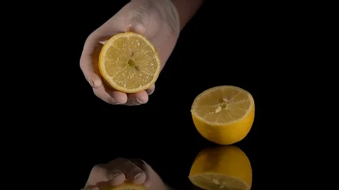 Hand squeezing lemon on dark background Stock Footage 84601663