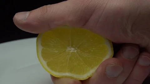 Hand squeezing lemon on dark background Stock Footage 85746122