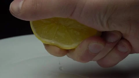 Hand squeezing lemon on dark background Stock Footage 85747268