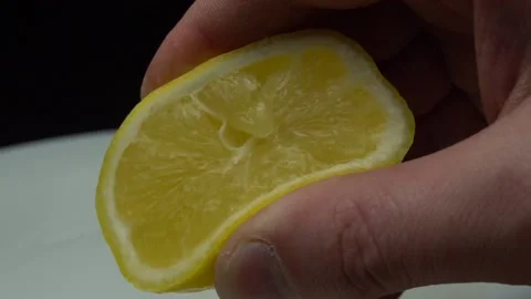 Hand squeezing lemon on dark background Stock Footage 85747654