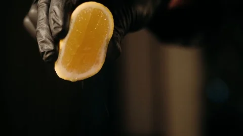 Hand squeezing a lemon on dark Stock Footage 125458454