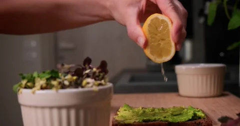 Hand squeezing lemon juice on avocado spread on bread, healthy eating concept. Video stock 152590811