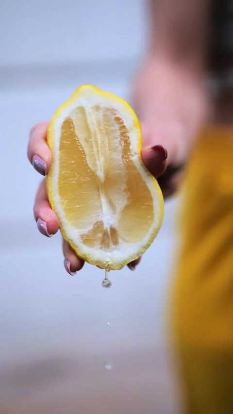 Hand squeezing lemon juice from half a lemon Stock Footage 276902532