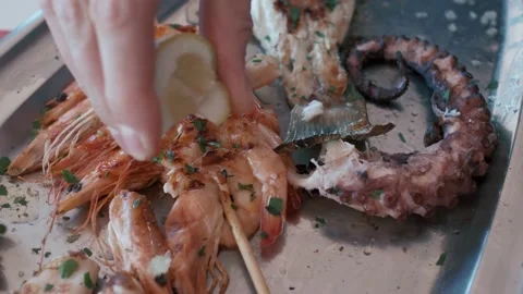 Hand squeezing a lemon juice on a plate with sea food. Stock Footage 236570403