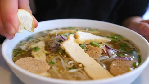 Hand Squeezing Lemon On Soup Pho With Vegan Soy Meat And Tofu. Closeup. Vídeos de archivo 109227072