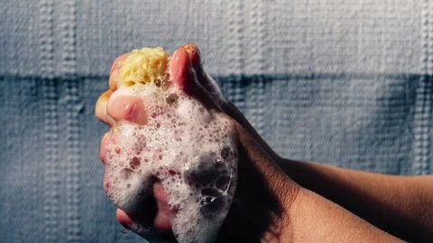 Hand squeezing natural sponge water soapy suds water Stock Footage 270567415