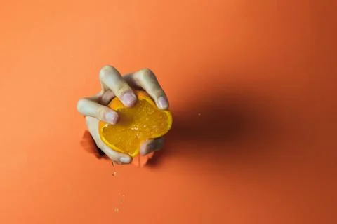 Hand squeezing an orange. Abstract concept Stock Photos