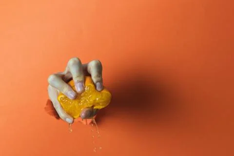 Hand squeezing an orange. Abstract concept Stock Photos