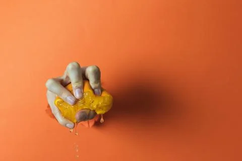 Hand squeezing an orange. Abstract concept Stock Photos