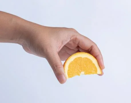 Hand squeezing orange fruit sliced on white background. Stock Photos