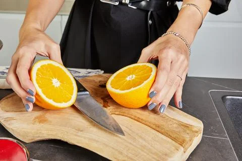 Hand squeezing orange half over a bowl on white background. Bright and vibran Stock Photos