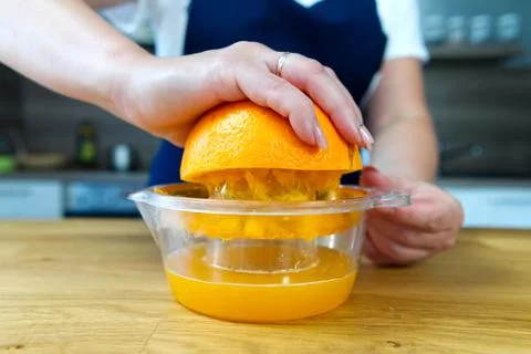Hand squeezing orange juice. Close up fresh drink making process. Stock Photos
