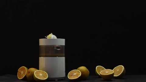 Hand squeezing oranges in a juicer on black background Stock Footage 131250993