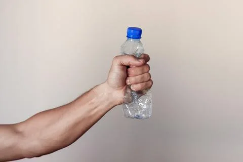 Hand squeezing Plastic Bottle representing movement against pollution and for Stock Photos