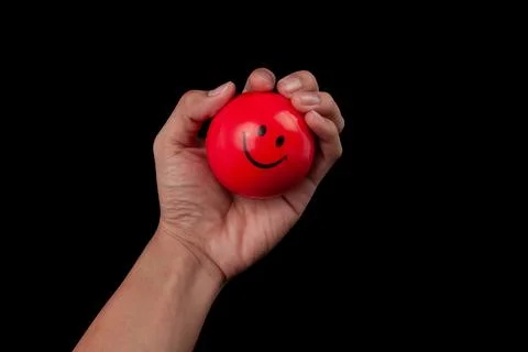 Hand squeezing a red stress ball isolated on black background with clipping.. Stock Photos