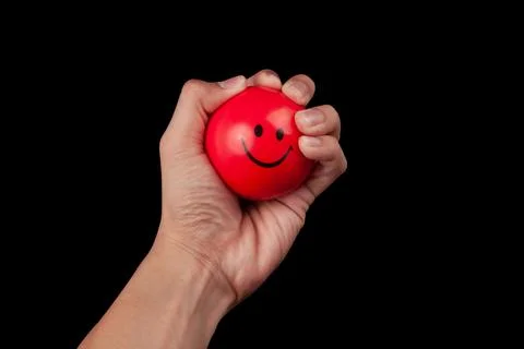 Hand squeezing a red stress ball isolated on black background with clipping.. Stock Photos