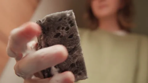 Hand squeezing soapy sponge toward camera during bathroom cleaning and personal Stock Footage 343533739