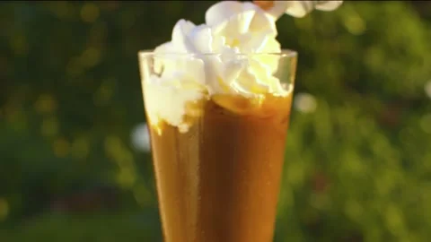 Hand squeezing whipped cream on iced coffee Stock Footage 137599114