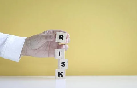 Hand stack up wooden cubes to make the word, Risk. Stockfoto's