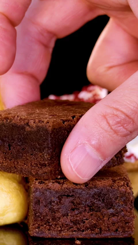 Hand Stacking Brownie on Dessert Display in Bakery Setting Stock Footage 315423461
