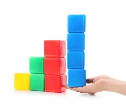 Hand stacking colorful plastic blocks in ascending order Stock Photos