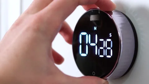 Hand starts a round kitchen electronic and mechanical timer for 5 minutes Stock Footage 150907389