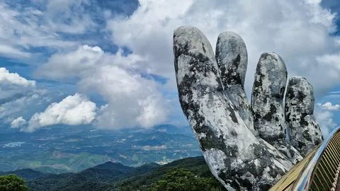 A hand statue made of rocks in the foreground with mountains in the background 스톡 사진