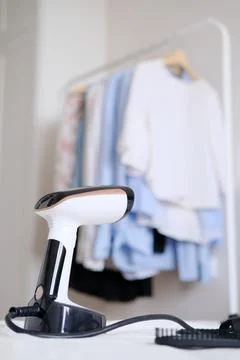 Hand steamer on the background of a rack with clothes in the room Stock Photos